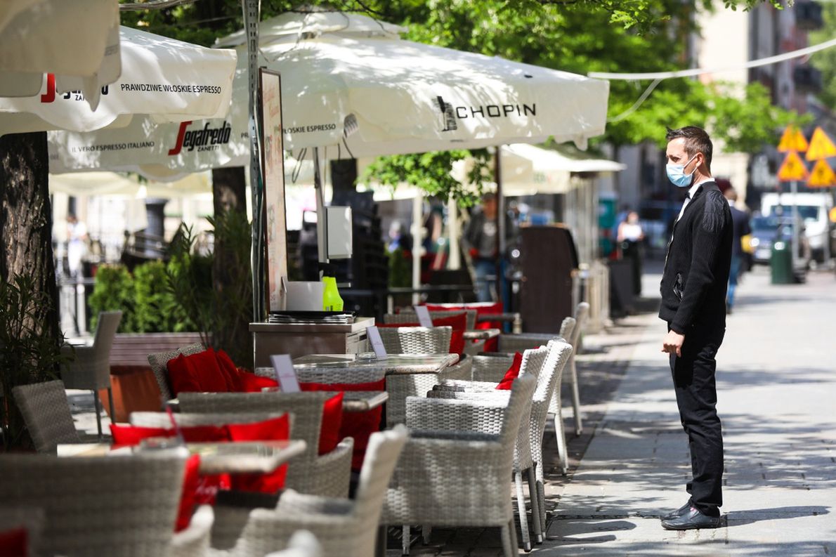 Kelner oczekuje na klientów przed restauracją w Krakowie