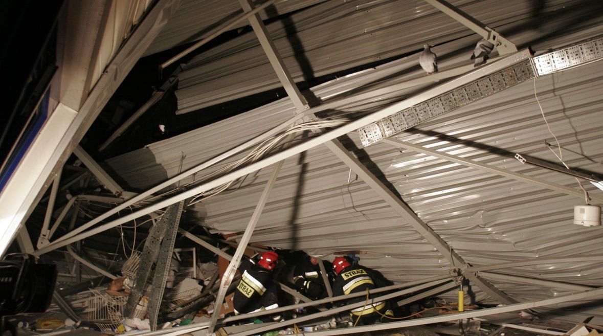 Strażacy usiłują dotrzeć do jednego z uwięzionych. W każdej chwili może spaść na nich reszta konstrukcji, 28 stycznia 2006 roku