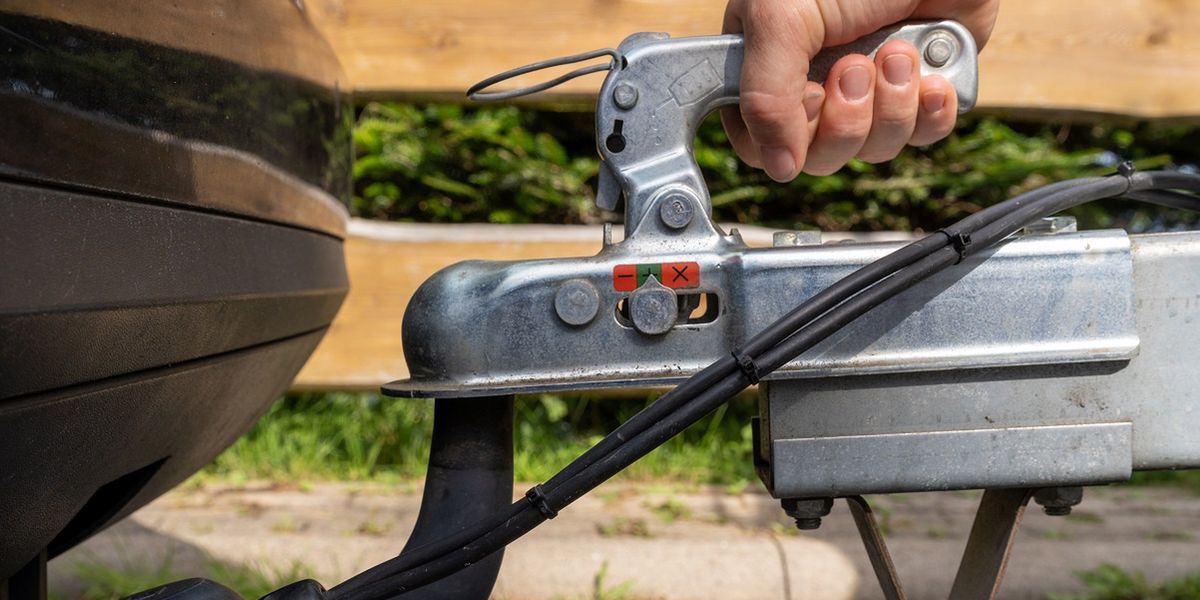 woman couple a trailer (i.s., hooked) into a ball-type tow hitchwoman's hand checks the fixation of the trailer closed hitch lock handle on the towing ball towbar of the car closeup, the safety of driving with a trailer on the roadconnection, pull, security, haul, camping, outdoors, journey, rear, woman, transportation, car, tow, metal, hitch, hook, vehicle, truck, equipment, trailer, transport, travel, bar, iron, steel, background, ball, street, road, close up, tow bar, hookup, service, caravan, hand, closeup, towing, construction, lock, towed, attached, hauling, automotive, towbar