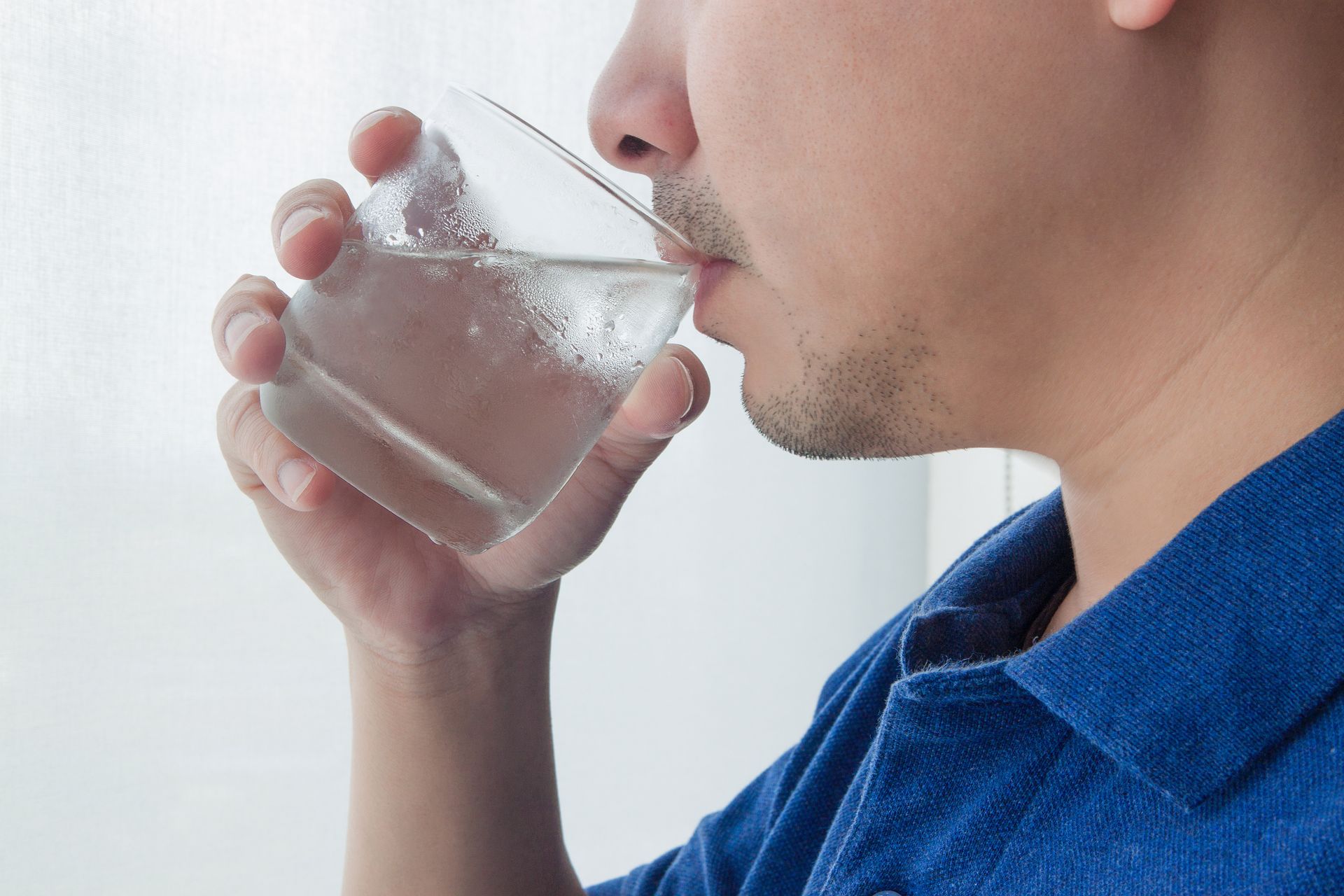 Запивать теплой водой. Человек пьет из стакана. Человек пьет воду из стакана. Пьет из стакана. Мужчина пьет воду.