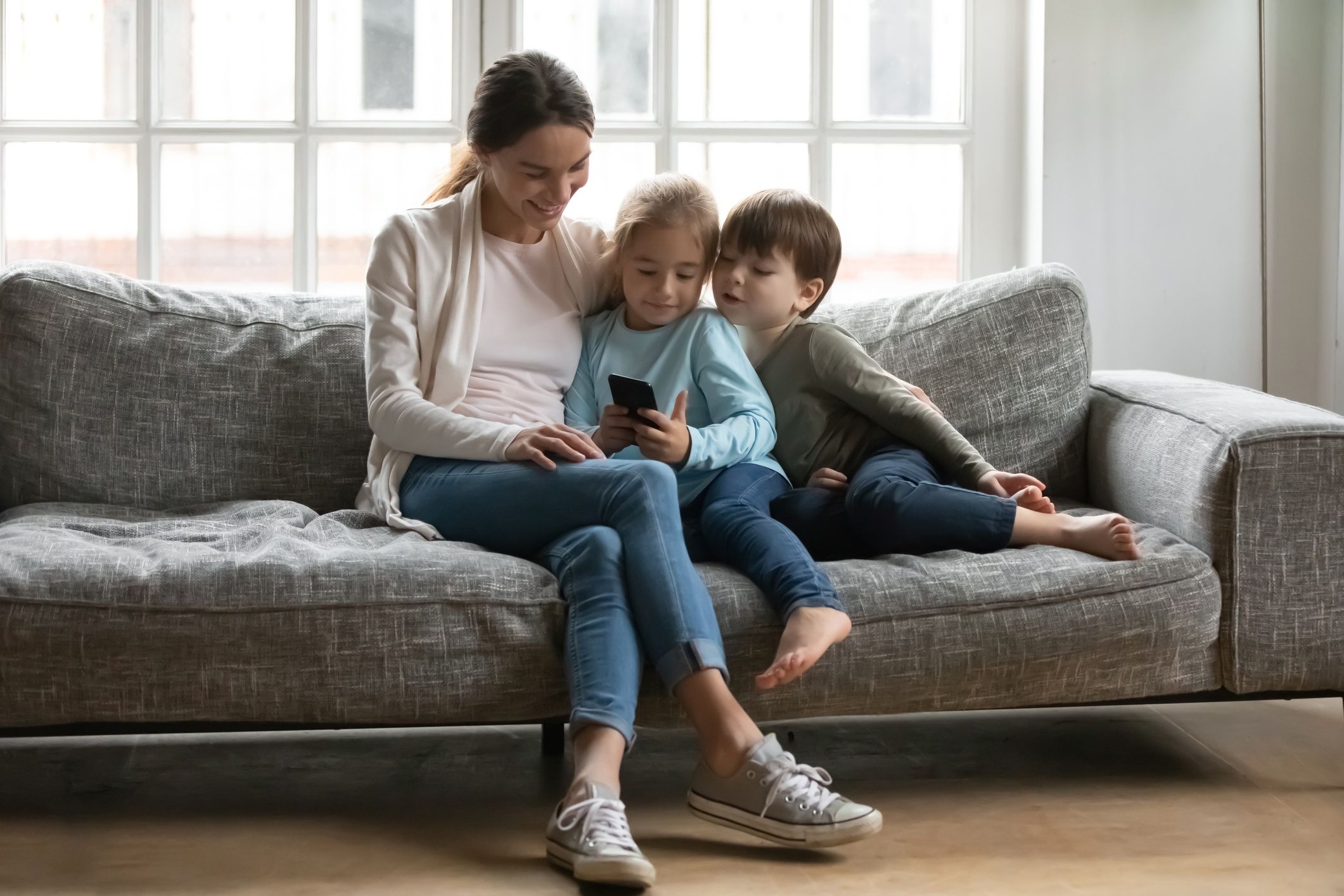 Szczęśliwa mama z dziećmi korzysta ze smartfona.