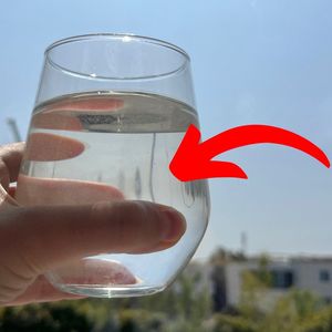 ręka trzymająca szklankę z wodą na słońcu
