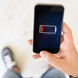 zbliżenie męskiej dłoni z rozładowanym telefonem