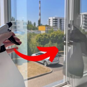 ręka ze spryskiwaczem przy oknie