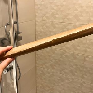 ręka z rolką papieru do pieczenia na tle kabiny prysznicowej