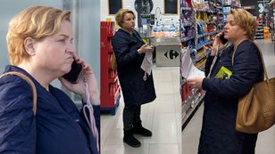 Zamyślona Katarzyna Bosacka buszuje po supermarkecie z telefonem przy uchu i z plikiem kartek w rękach