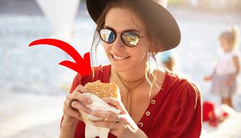 młoda kobieta w kapeluszu trzyma hamburgera