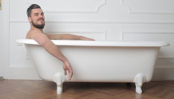 Mężczyzna wystaący z wanny widzianej z boku