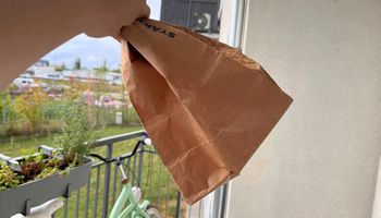 ręka trzymająca papierową torbę na balkonie