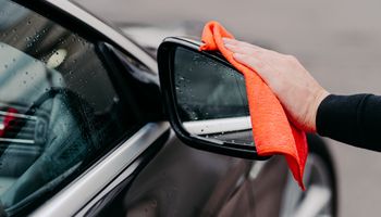 ręka wycierająca lusterko samochodowe ściereczką