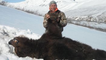 Mężczyzna dumnie pozuje z niedźwiedziem, którego zabił w czasie hibernacji. Zwierzę nie miało szans