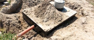 Szambo betonowe wkopane w ziemię i gotowe do podłączenia