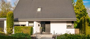 Niewielki, prosty dom jednorodzinny otoczony ogrodem.