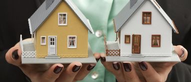 dwie makiety domów na dłoniach