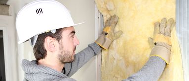 mężczyzna wykonuje cieplenie ścian od wewnątrz wełną mineralną