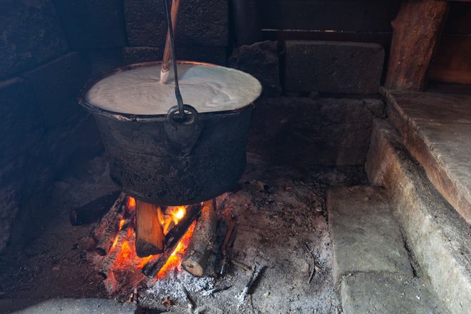 Bacówka w Jabłonce nad Czarną Orawą i okolice. Gar z gotującym się mlekiem z pianą i drewnianą łyżką nad płonącym ogniskiem.  