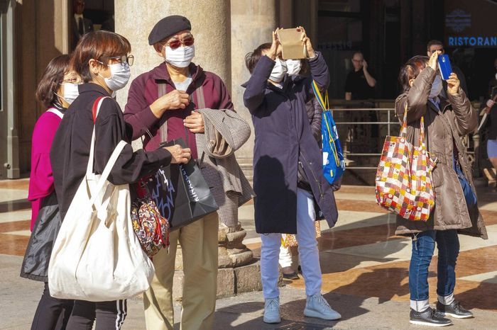 Italy, Milan, february 24, 2020 : Far eastern tourist in Duomo square taking pics at the Cathedral while covering their mouth and nose as prevention from corona virus desease 

Photo © Marco Vacca/Sintesi