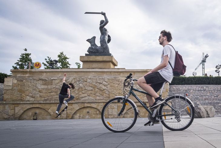 Na zdjęciu: rowerzysta na tle pomnika warszawskiej Syrenki