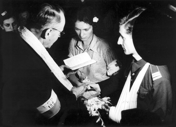 Fotografia z Powstania Warszawskiego. Śródmieście Północne. Ślub sanitariuszki Alicji Treutler "Jarmuż" i plut. pchor . Bolesława Biegi "Pałąka" w kaplicy przy Moniuszki 11. Ślubu udziela kpt. ks. Wiktor Potrzebski "Corda”. W lewym górnym rogu Danuta Cytling "Przemsza", „Danka I”.