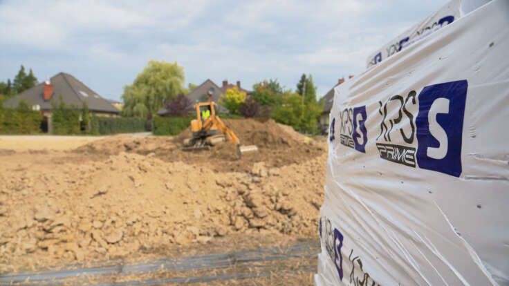 koparka podczas budowy fundamentów domu na tle produktu TB