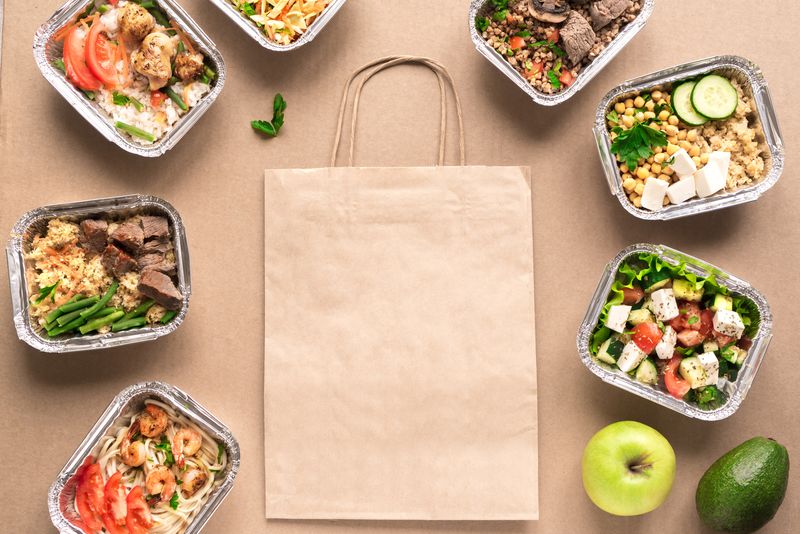 Healthy food delivery. Take away of organic daily meal, copy space. Clean eating concept, healthy food, fitness nutrition take away in foil boxes, top view, flat lay.