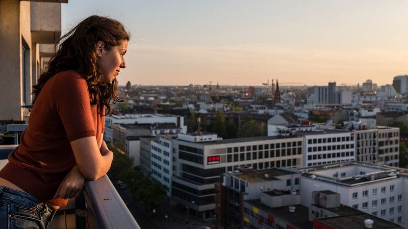 jak pochodzenie wpływa na charakter - kobieta patrząca z balkonu na miasto