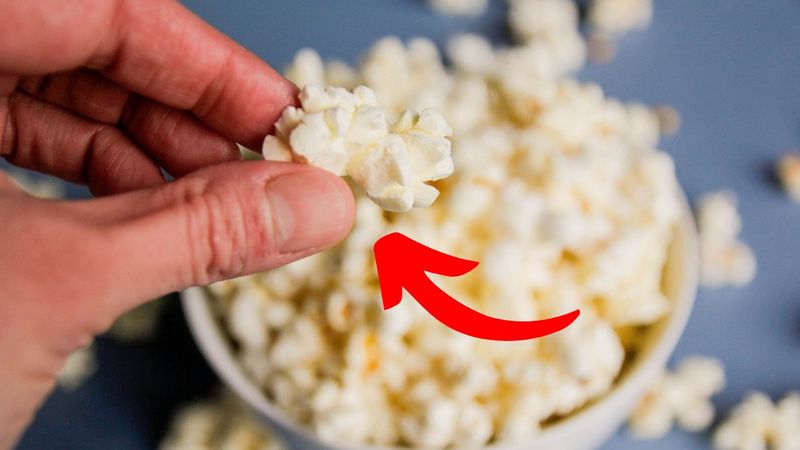 trik na puszysty popcorn - ręka wyjmująca kawałek popcornu z miski