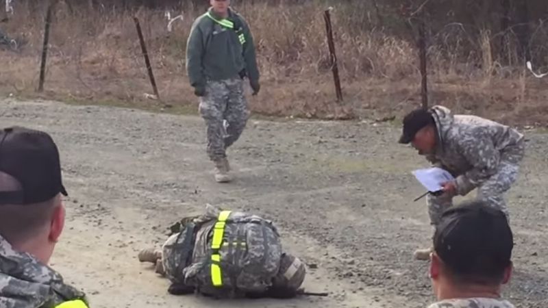 Kobieta należąca do armii pada na ziemię. Obserwuj uważnie reakcję żołnierzy stojących wokół niej