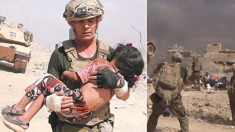 Żołnierz biegnie wśród strzałów do małej dziewczynki. Wokół widzi ciała jej zamordowanej rodziny.