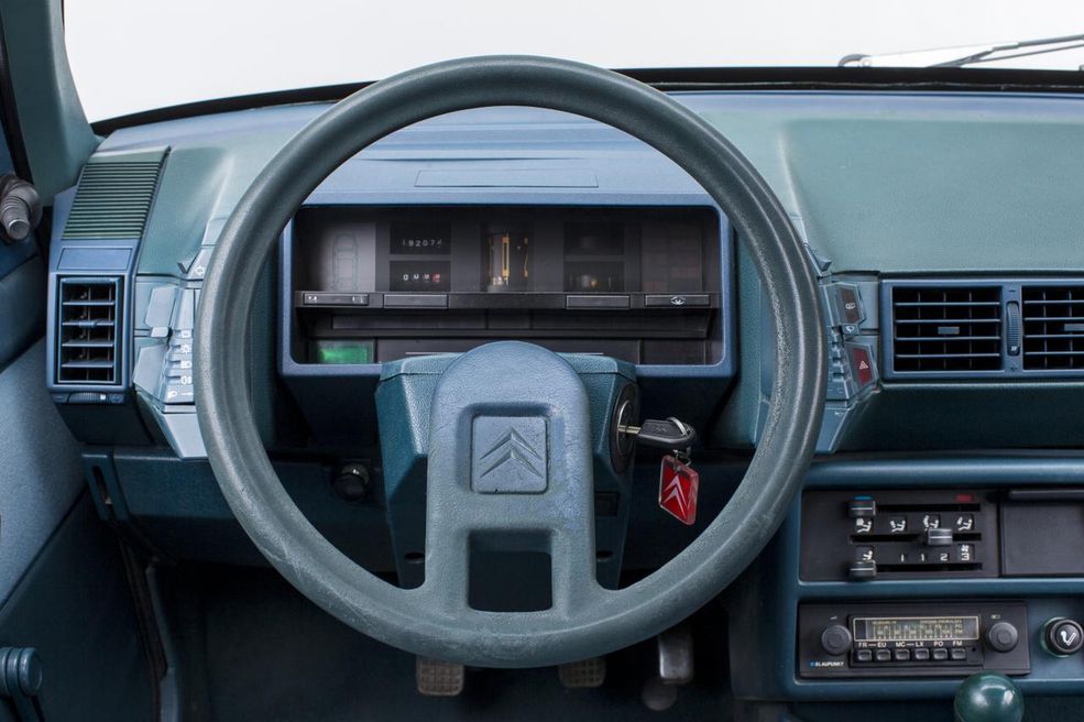 Citroen BX
Jako następca GSA, BX przejął po swoim poprzedniku niektóre rozwiązania, w tym zapewniające niebywały komfort hydropneumatyczne zawieszenie oraz niecodzienny projekt deski rozdzielczej. Choć radio i dźwignia hamulca ręcznego otrzymały bardziej logiczny przydział miejsca, obsługa kierunkowskazów, wycieraczek czy ogrzewania tylnej szyby wciąż odbywała się za pomocą bloków przyciskowych, które wyrastały zza kierownicy po obu stronach. Prędkościomierz wciąż miał charakter bębenkowy, a komu było mało, mógł zdecydować się na rzadko dziś spotykaną wersję BX Digit, która oferowała w pełni cyfrowe zegary, pozwalające poczuć się niemal jak w myśliwcu. Fantazja godna reżysera filmów sci-fi została jednak brutalnie zakończona wraz z liftingiem, kiedy powiedziano stanowcze „assez!” (fr. dość) – zegary przekształcono na analogowe, a kosmiczne przełączniki zastąpiono tradycyjnymi manetkami.
