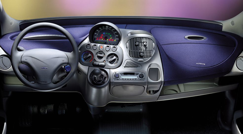 Fiat Multipla
Zestawienie kończymy autem, które każdy doskonale zna z zewnątrz. A co z wnętrzem? Jeśli myśleliście, że Fiat Multipla wyróżnia się tylko swoim osobliwym designem nadwozia, jesteście w błędzie. Zaglądając do środka, również można przeżyć szok. Patrząc na nagromadzenie niemal wszystkich instrumentów na konsoli środkowej, odnoszę wrażenie, że tuż przed pokazaniem projektu zarządowi, ktoś przypadkiem trącił makietę, przez co wszystkie elementy rozsypały się po podłodze. A że czasu było mało, umieszczono je na opak. Projektanci zdecydowali się także znacząco wyróżnić wewnętrzny uchwyt drzwi, który swoim rozmiarem przypomina niewielki balkonik. Ostatnim, ale bardzo praktycznym "smaczkiem", jest fakt, że ten osobliwy, włoski minivan dysponował trzema fotelami w pierwszym rzędzie, co czyniło go autem 6-osobowym.