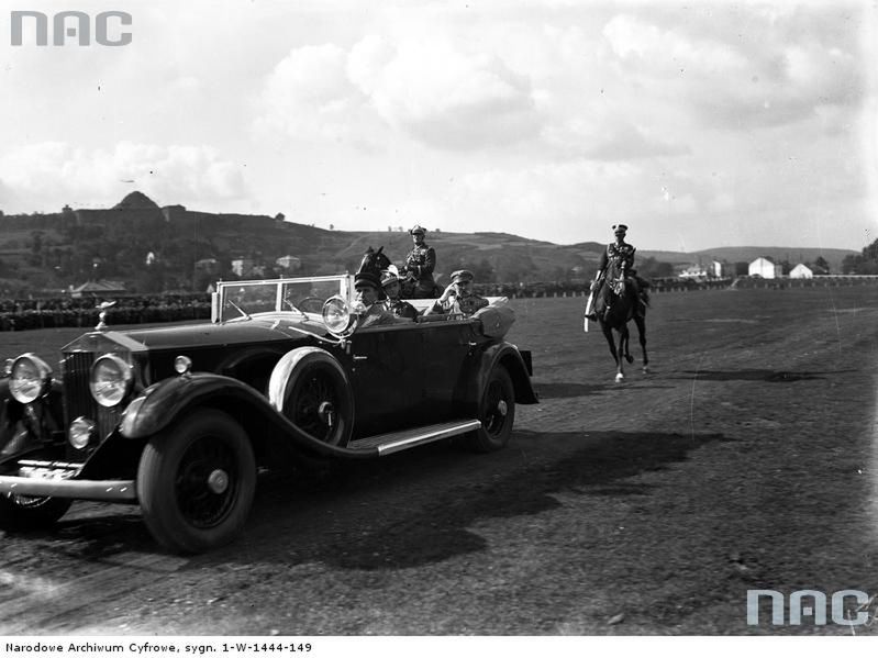 Marszałek Józef Piłsudski w samochodzie Rolls-Royce w towarzystwie płk. Witolda Warthy przejeżdża przez Błonia. Z lewej na koniu gen. Gustaw Orlicz-Dreszer.
Data: 10.1933
Miejsce: Kraków
