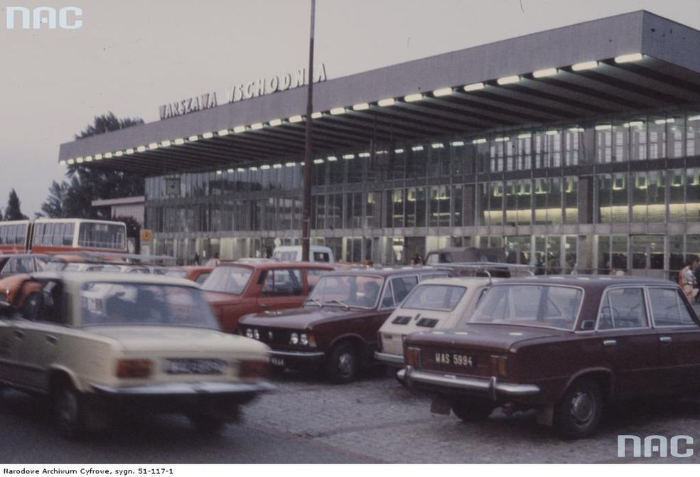 Widok zewnętrzny budynku Dworca Wschodniego w Warszawie. Widoczne samochody - Fiat 125p, Fiat 126p i Wartburg 353 zaparkowane przed budynkiem.