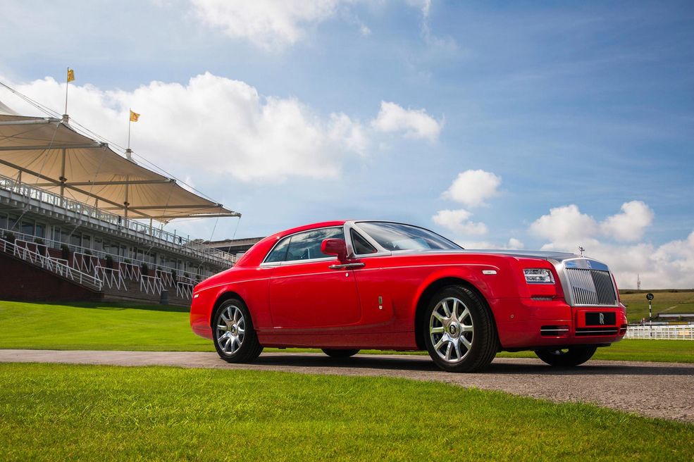 Rolls-Royce Phantom Coupé Al-Adiyat
Ponownie coupé i ponownie soczysta czerwień. Tym razem jest to jednak większy krewny Wraitha - Phantom Coupé. Samochód ten zwiastował nadejście całej serii Al-Adiyat, nazwanej po dźwięku, który wydają kopyta konia uderzające o kamienie. Miały w niej zawierać się: 1 Phantom Coupé, którego widzicie na zdjęciach oraz 9 Wraithów.
Auto pokryte jest czerwonym lakierem, który uzupełniony jest o motywy przedstawiające konie i elementy z nimi związane, w tym podkowy. Soczysta czerwień widoczna jest także wewnątrz jako motyw uzupełniający białą tapicerkę. Pod maską znajdziemy oczywiście 6,75-litrowe V12, które dysponuje potężnym momentem obrotowym na poziomie 720 Nm.