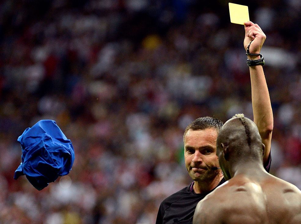 SPORT - ZDJĘCIE POJEDYNCZE - MIEJSCE 1 BARTŁOMIEJ ZBOROWSKI (Polska Agencja Prasowa PAP). Piłkarz reprezentacji Włoch Mario Balotelli (P) otrzymuje żółtą kartkę od sędziego Stephane'a Lannoya (L) za zdjęcie koszulki po strzeleniu drugiego gola w półfinałowym meczu z Niemcami podczas mistrzostw Europy UEFA EURO 2012 w Warszawie. Warszawa (Polska), 28 czerwca 2012 r.