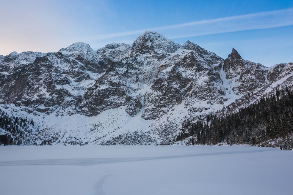 Canon 5D Mark III + Tokina AT-X PRO FX SD 16-28 mm f/2.8 | 16 mm f/9, 1/80 s, ISO 250. Tatry, Morskie Oko. Dzięki dużemu polu widzenia obiektywu Tokiny, mogłem objąć zarówno tatrzańskie szczyty i zamarzniętą taflę Morskiego Oka. Kompozycyjnie jest to klasyczne ujęcie, za pomocą linii na śniegu oraz drzew prowadzę wzrok widza do centrum kadru.