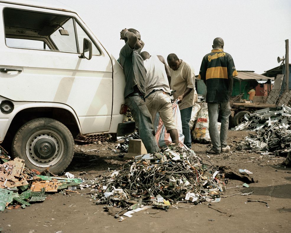 Agbobloshie, Accra, Gana: Młody mężczyzna podczas przerwy przed składowiskiem. Czeka, żeby zebrać materiały, które zostaną spalone w celu odzyskania elementów metalowych na sprzedaż.