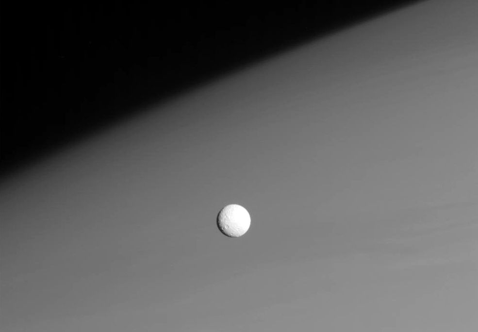 Niewielki lodowo-skalisty księżyc Mimas (średnica: 396 km) na tle
górnych warstw atmosfery Saturna. Jest on najmniejszym znanym ciałem niebieskim zdolnym utrzymać kształt bliski sferycznemu dzięki własnej grawitacji. Zdjęcie wykonane z odległości ok. 915 tys. km od Mimasa.