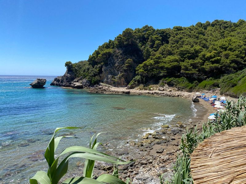 Spokojna Yaliskari Beach otoczona zielonym wzgórzem