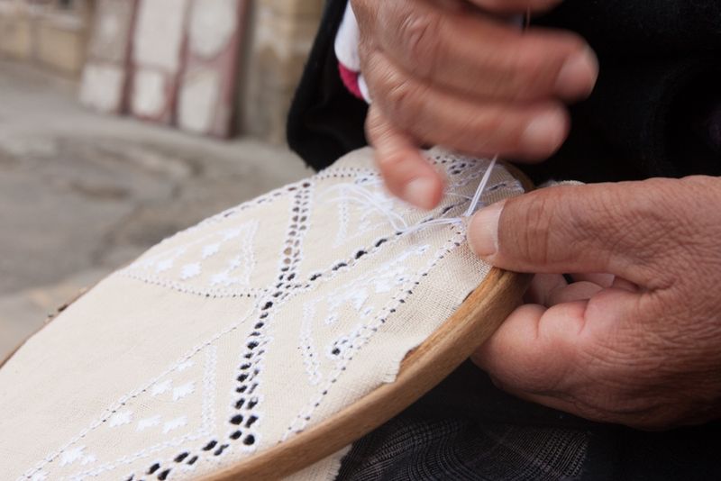 Kobiece dłonie wykonujące koronkową robótkę