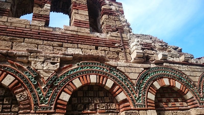 Fragment muru cerkwi Archaniołów Michała i Gabriela z ceramicznymi elementami ozdobnymi