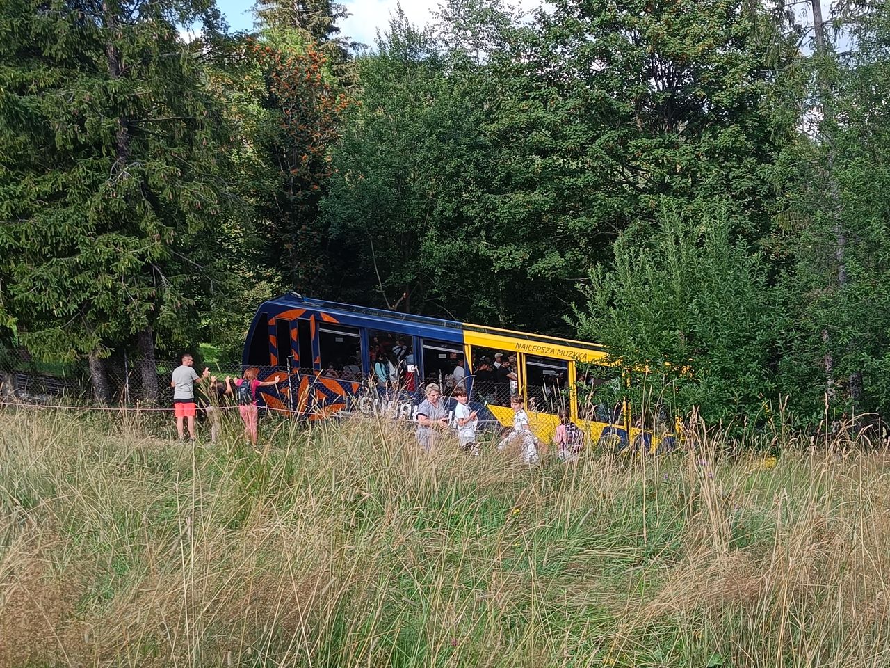 Turyści na czarnym szlaku obserwujący  wagonik kolejki