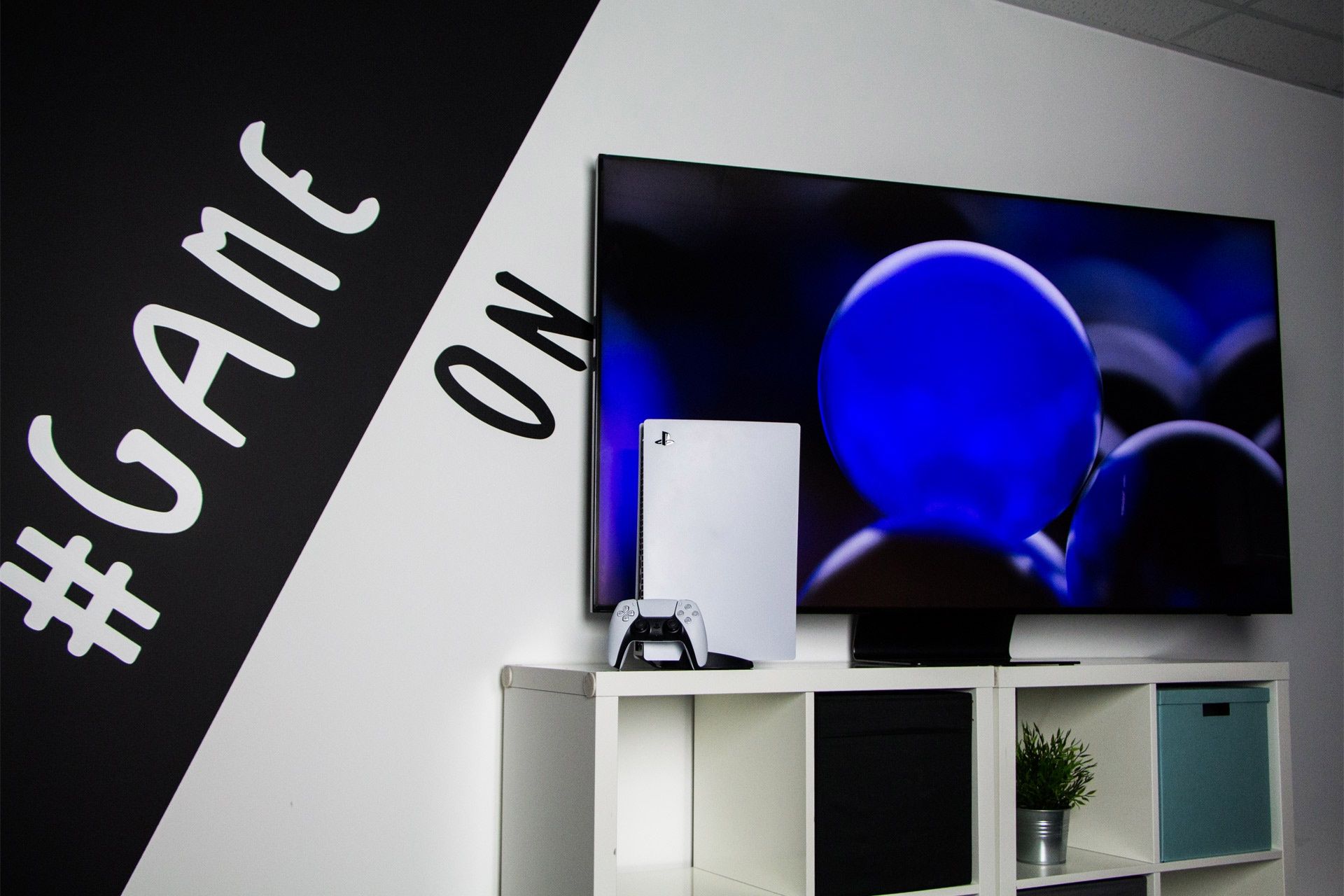 PS5 na tle ściany i telewizora firmy Samsung