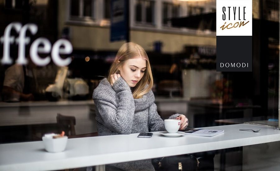 Zamyślona dziewczyna w kawiarni przy kawie wpatrująca się w telefon.
